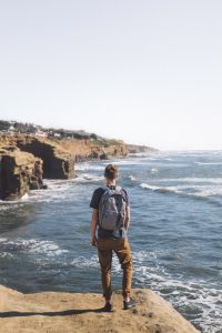 boy on cliff with backpack